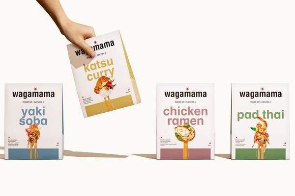 A hand picking up a meal kit out of four different meal kits