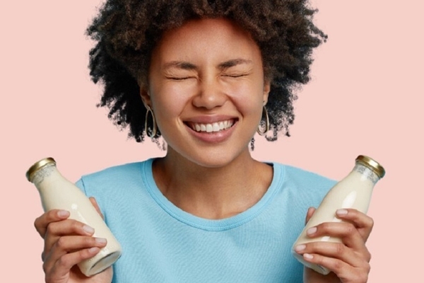 a young girl holding two bottles of plant based milk