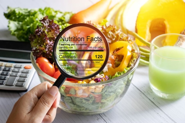 Image nutrition data inside magnifying glass held over a bowl of vegetable and fruit