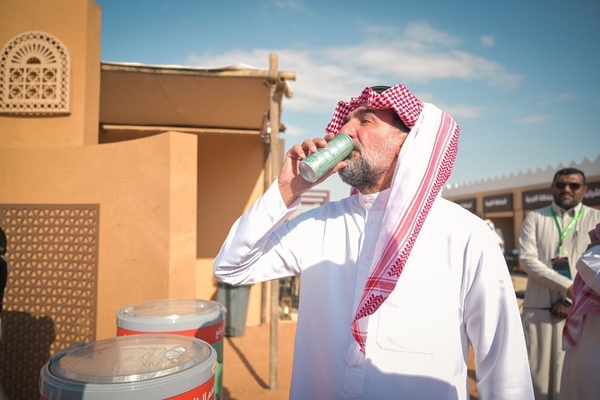 Image an Arab man drinking cola from a green can.