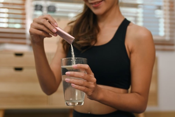 Image A woman taking collagen supplements at the gym.