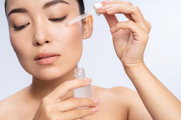 A woman putting a serum on her cheek.