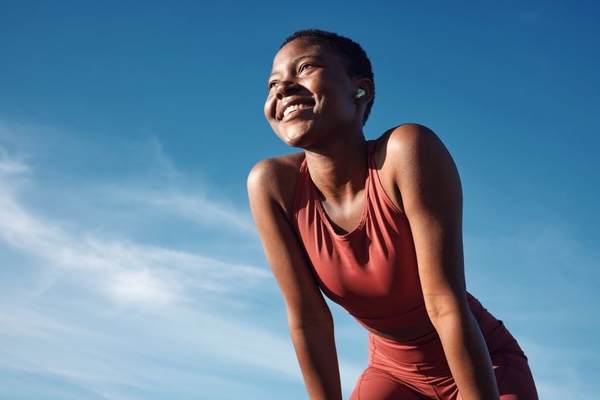 Image fit woman in gym clothes under blue sky smiling