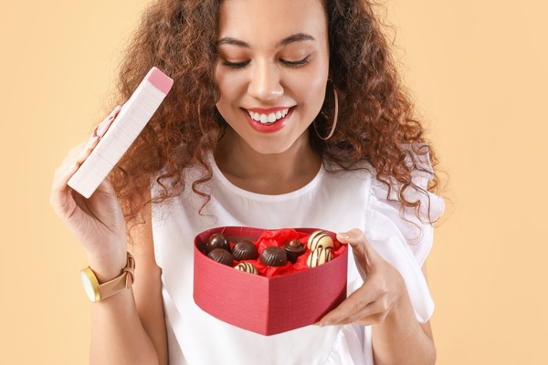 Image Woman opening chocolate box in heart shape.