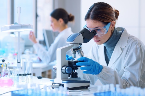 Image A female scientist looking into a microscope.