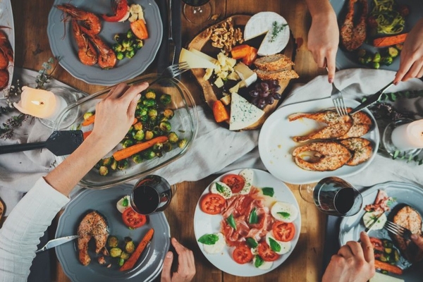 Several people sitting around a table filled with Mediterranean diet foods, including fish and vegetables.