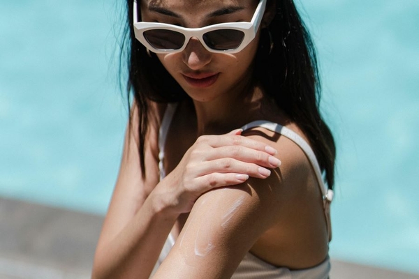 Image A woman putting sunscreen on her arm.