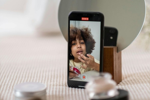 Image Person recording TikTok video applying makeup