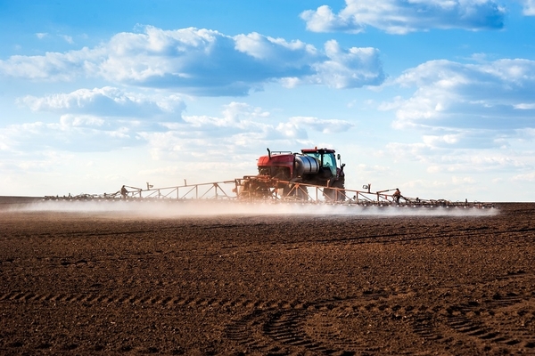 Image A tractor spraying pesticide in the field.