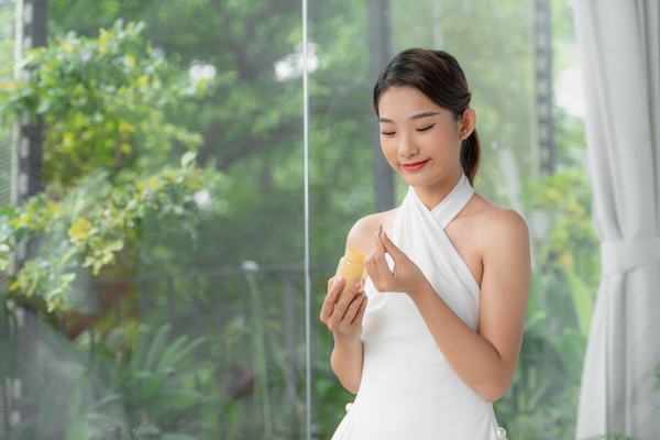 A woman smiles and gets ready to take a yellow supplement.