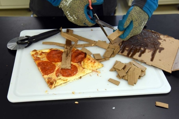 Image A person cutting a pizza box.