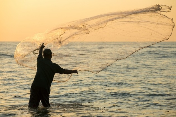 Image fisherman throwing net in the sea