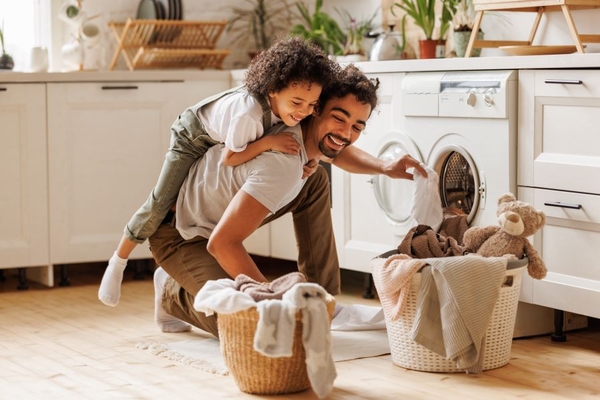 father and son doing laundry having fun