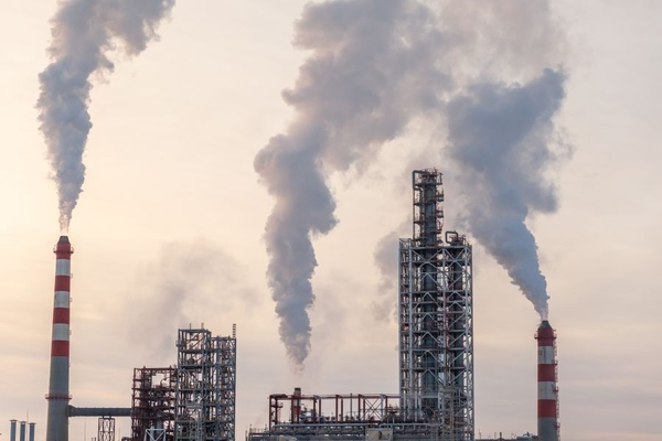 Image A petrochemical plant with smoking coming out of the top.