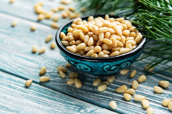 pine nuts in a black bowl with green leaves on the side