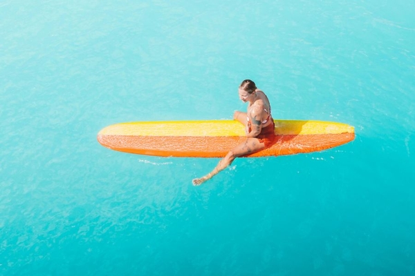 Image woman on a surfboard in the sun in the sea