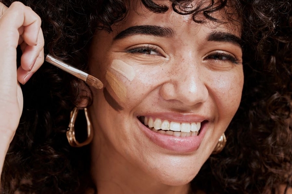 woman applying foundation on her face