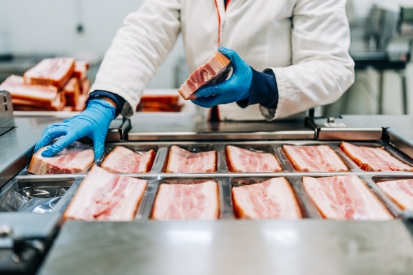 Image Factory worker lays out pork cuts on production line.