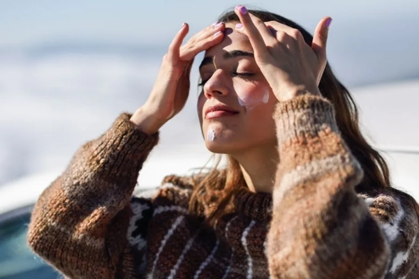 Image woman in snow applying sunscreen