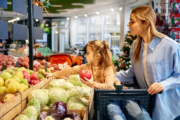 Image Little girl choosing apple with her mom while grocery shopping together