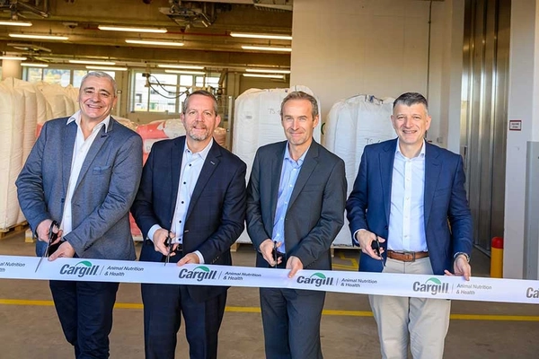 Image four men in suits cutting white ribbon inside factory