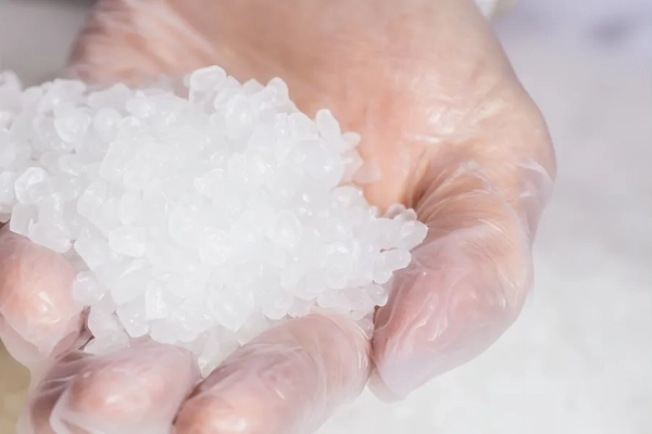 Image A hand in glove holding plastic granules.