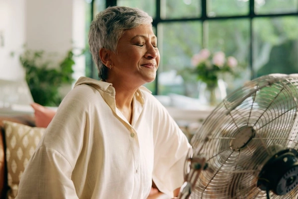 Image Middle aged woman smiles as fan blows on face