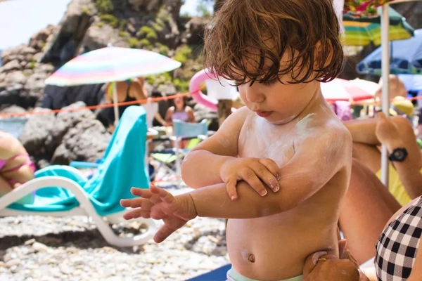 Image baby applying sunscreen on the beach