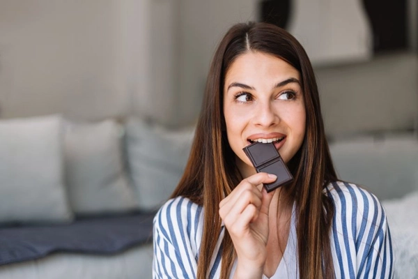 Young woman eating dark chocolate.