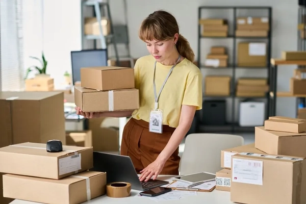 Image A person holding a box and a computer.