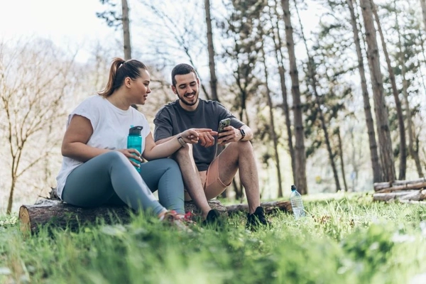 Image Man and woman checking phone outside