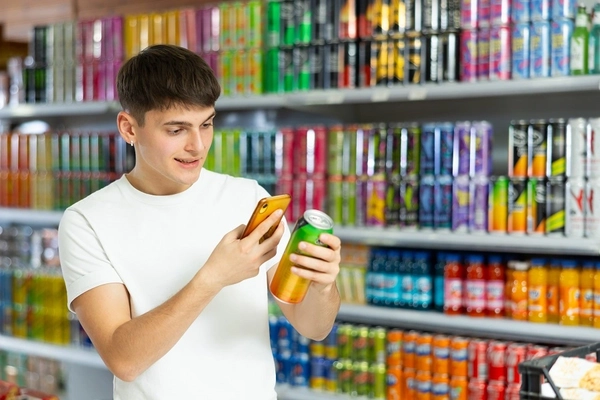 teenage boy with energy drink can in supermarket