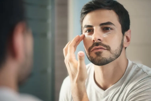 Image A man putting cream under his eyes.