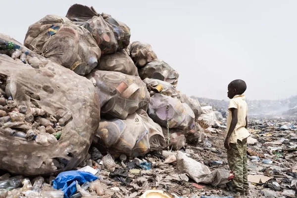 A child standing next to a pile of garbage