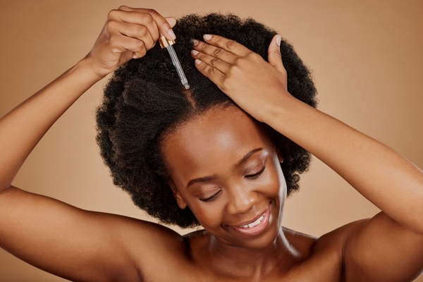 Woman applies hair serum to hair roots