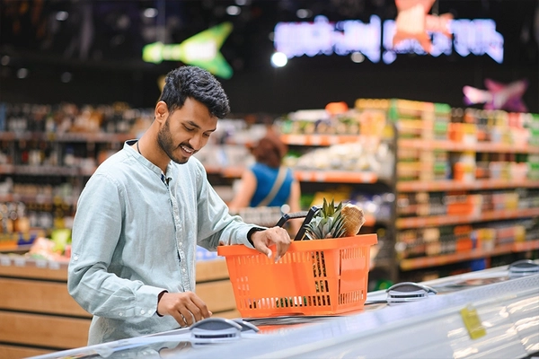Image Indian man standing at grocery shop looking into freezer