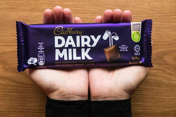 Image Hands holding Cadbury chocolate bar.