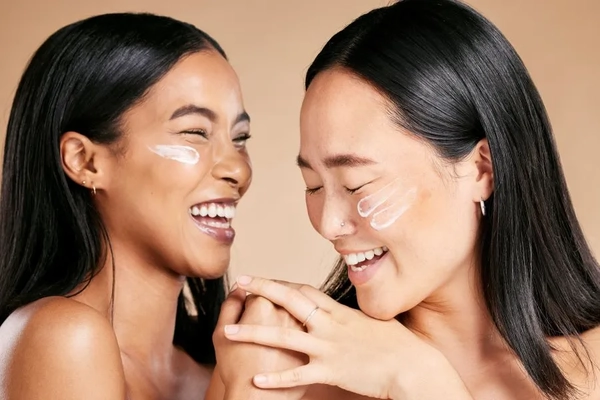 Image Two women smiling with sunscreen on their cheeks.