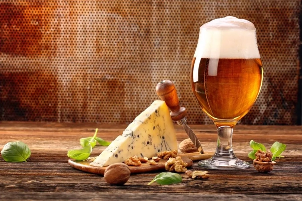 Cheese and beer on a wooden table.