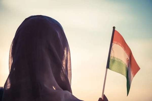 Image Woman wearing a hijab and holding an Iranian flag