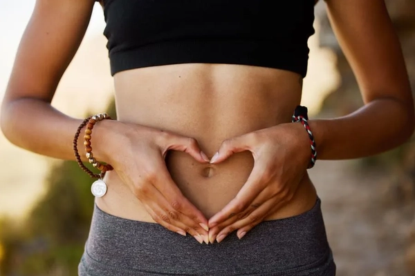 woman holding heart hands over stomach