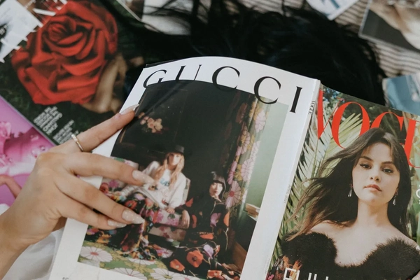 A girl holding a magazine with a Gucci advertisement.