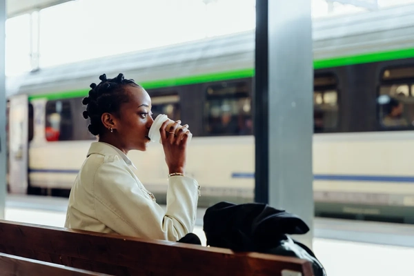 Image woman drinks coffee waiting for train