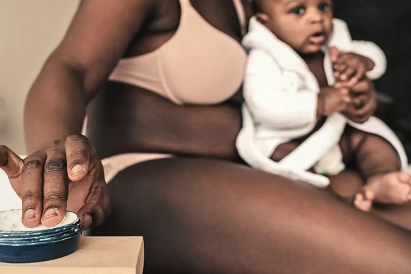 Woman applying skin cream to herself and baby