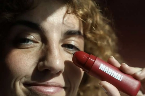 Image model holds up red cosmetic bottle