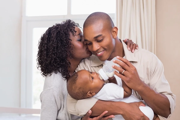 Couple feeding baby milk from a bottle Couple feeding baby milk from a bottle