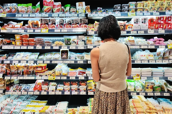 Image Asian woman in supermarket selecting food products.