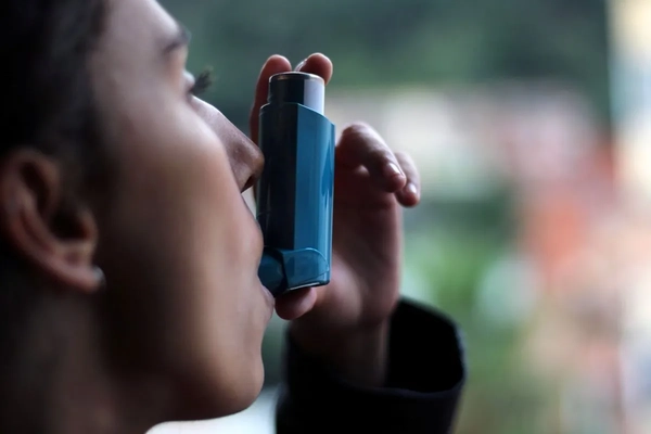 Image woman using inhaler for asthma attack