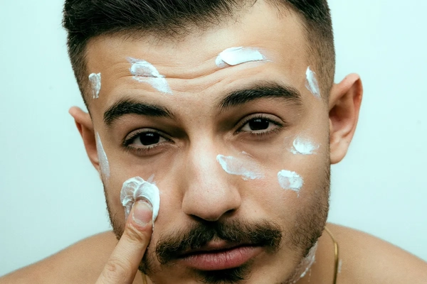 Image A man with dots of skin cream around his face.