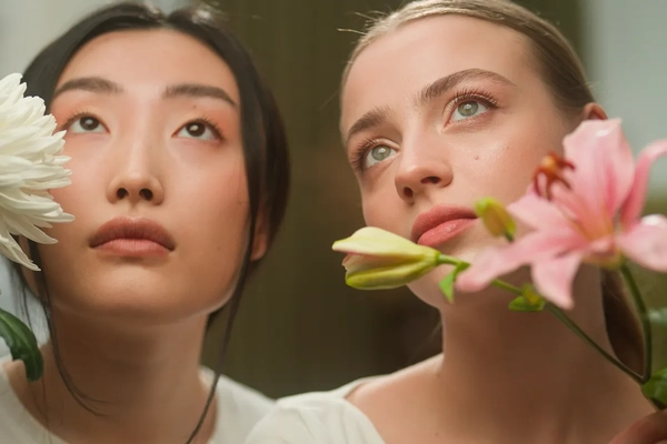 Image Two women posing in front of a light background with florals